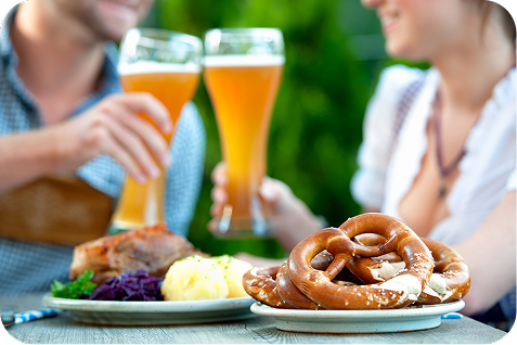 プレッツェルやドイツ料理を囲んでビールで乾杯するイメージ